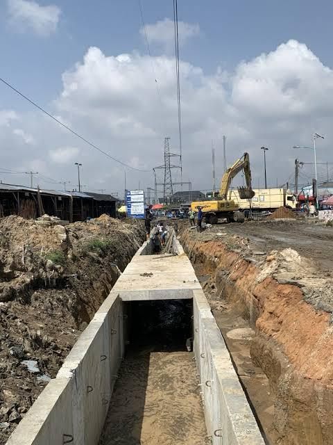 Large concrete storm drain installation with excavator on site